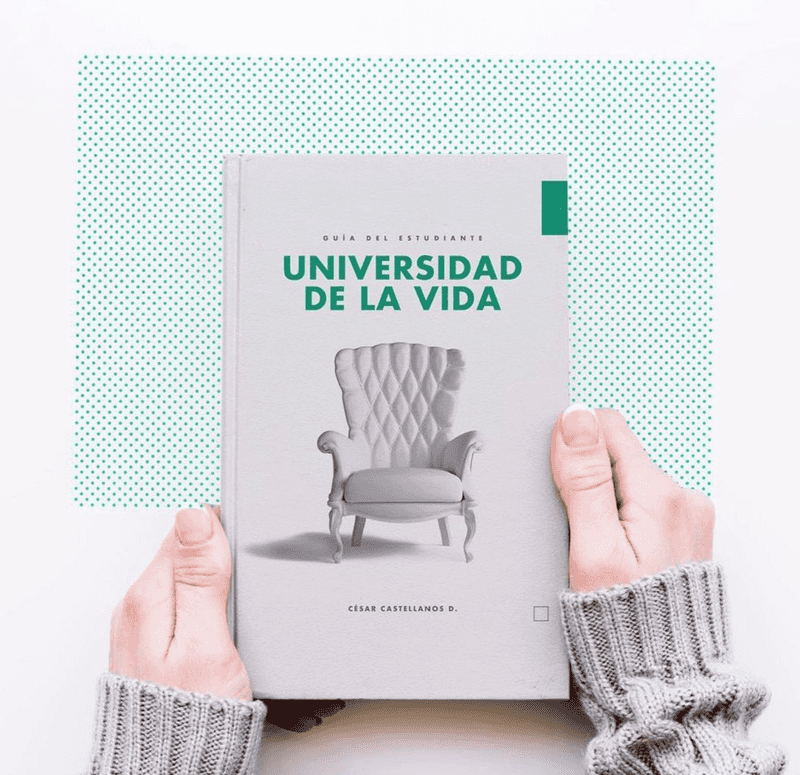 Las manos de una estudiante sosteniendo el libro de Universidad de la Vida
